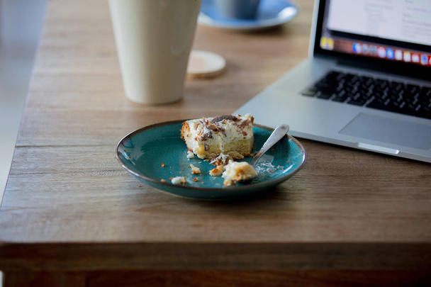 Computadora portátil y plato con pastel en un talbo
 - Foto, Imagen