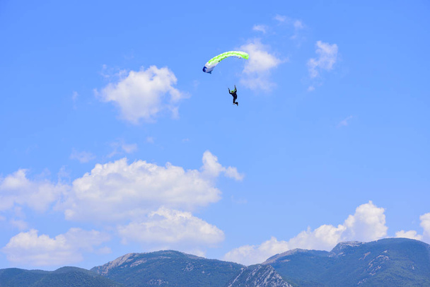 parachutiste descend contre un ciel bleu, en arrière-plan les montagnes
 - Photo, image