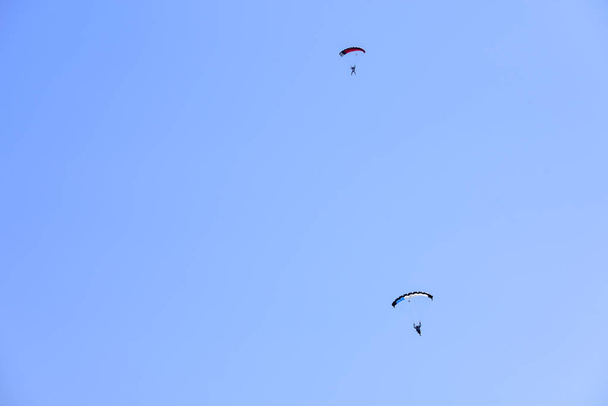 Deux parachutistes descendent contre un ciel bleu
. - Photo, image