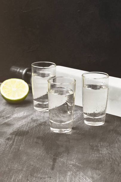 Cold vodka in shot glasses on a black background. Toned - Photo, image