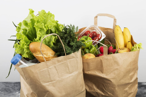 Various healthy food in paper bag on gray background - Фото, зображення