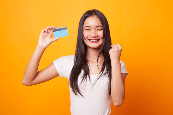 Young Asian woman fist pump with blank card on bright yellow background - Fotografie, Obrázek