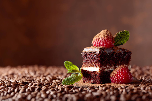 Close-up de bolo de chocolate com framboesa e hortelã em um bacground marrom. Espaço de cópia
. - Foto, Imagem