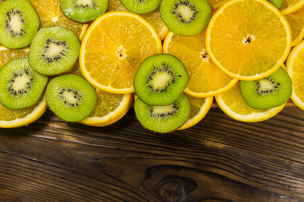 Sliced kiwi fruits and oranges on wooden table. Top view, copy space - Photo, Image