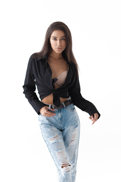 Young cool hipster girl in black shirt and blue banana jeans on white background. Fashionable modern style - Foto, Imagem