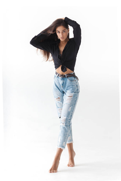 Young cool hipster girl in black shirt and blue banana jeans on white background. Fashionable modern style - Valokuva, kuva