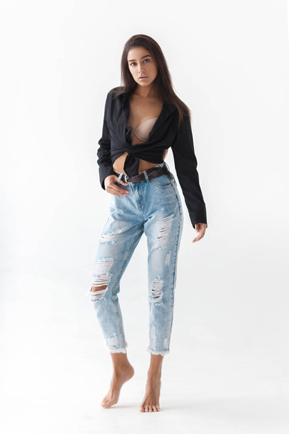 Young cool hipster girl in black shirt and blue banana jeans on white background. Fashionable modern style - Valokuva, kuva