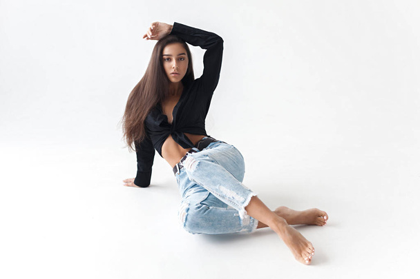 Young cool hipster girl in black shirt and blue banana jeans on white background. Fashionable modern style - Foto, Imagem