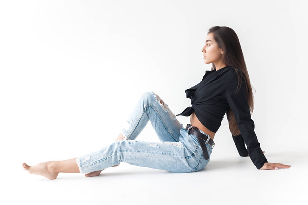 Young cool hipster girl in black shirt and blue banana jeans on white background. Fashionable modern style - Фото, зображення