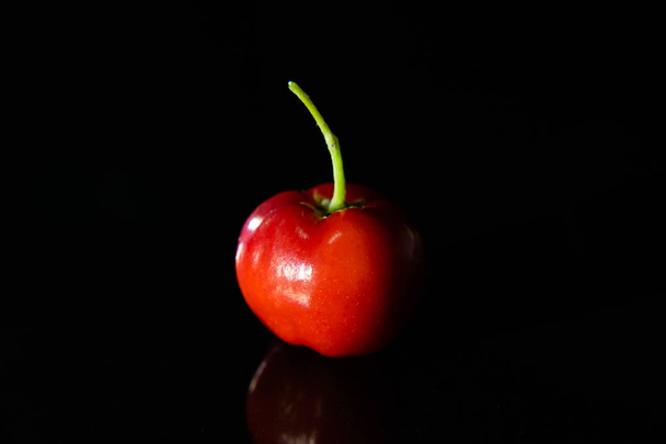 Nahaufnahme von Acerola-Kirschfrüchten auf schwarzem Hintergrund. (Malpighia emarginata)) - Foto, Bild