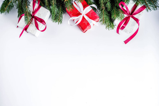 Kerstmis achtergrond voor wenskaart, met fir tree branch en geschenken dozen met linten, op witte achtergrond bovenaanzicht kopie ruimte voor tekst - Foto, afbeelding
