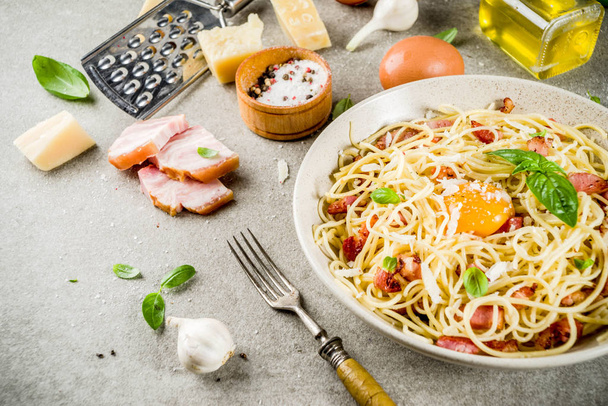 Traditional italian pasta, spaghetti carbonara with bacon, creamy sauce, parmesan cheese, egg yolk and fresh basil leaves grey stone background copy space - Photo, Image