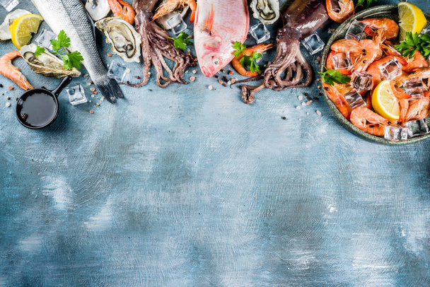 frische rohe Meeresfrüchte Tintenfisch Garnelen Austernmuscheln Fisch mit Gewürzen von Kräutern Zitrone auf hellblauem Hintergrund kopieren Raum von oben  - Foto, Bild