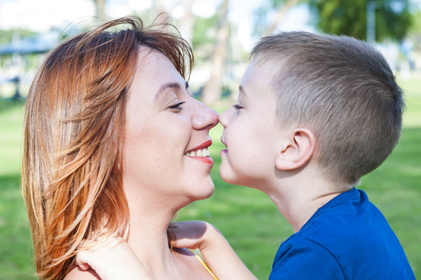 Young and beautiful Caucasian woman and her son touching each other nose to nose, face to face close up portrait, mother child love family concept. Look at each other. Single mother. - Photo, Image