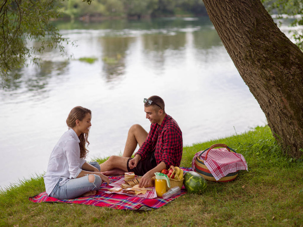 Couple in love enjoying picnic time drink and food in beautiful nature on the river bank - Fotoğraf, Görsel