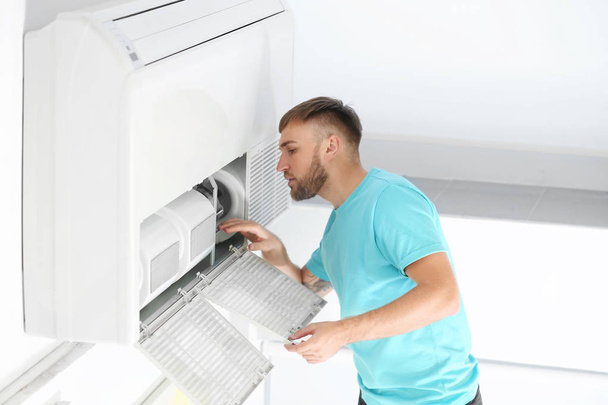 Young man fixing air conditioner at home - Foto, Imagen