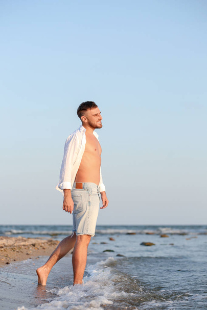 Young man enjoying sunny day on beach - Foto, afbeelding