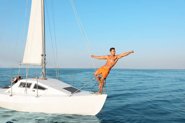 Young man and his beautiful girlfriend in bikini on yacht. Happy couple during sea trip - Zdjęcie, obraz