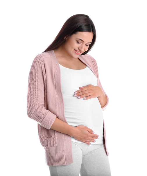 Young pregnant woman holding hands on belly against color background, closeup - Foto, afbeelding