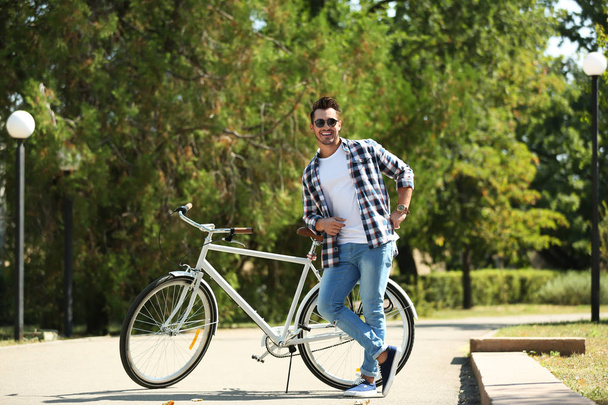 Handsome young hipster man with bicycle in park - Fotoğraf, Görsel