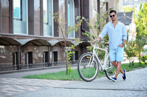 Handsome young hipster man with bicycle outdoors - Фото, изображение