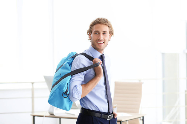 Joven hombre de negocios guapo sosteniendo bolsa de fitness en la oficina. Gimnasio después del trabajo
 - Foto, imagen