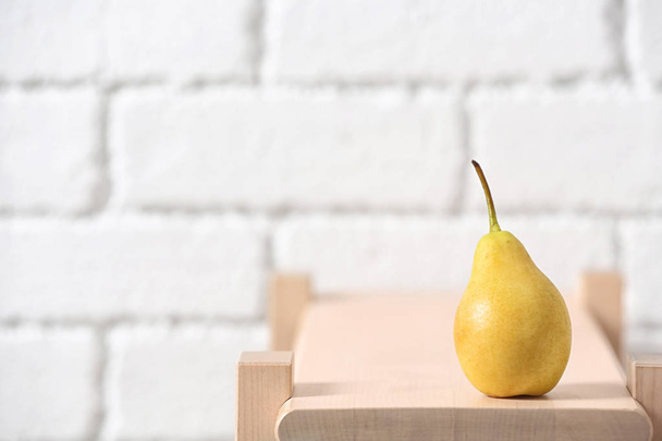 Ripe pear on wooden shelf against blurred background. Space for text - Foto, Imagen