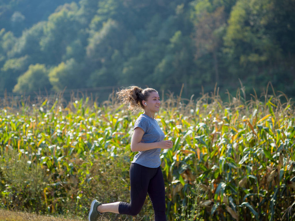 young woman enjoying in a healthy lifestyle while jogging along a country road, exercise and fitness concept - Fotoğraf, Görsel