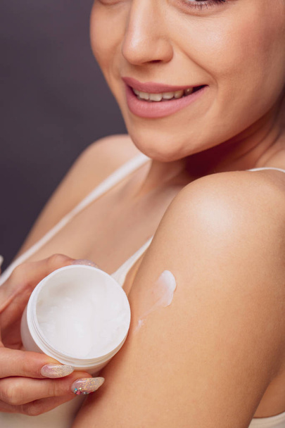 Protection and health care. a young smiling woman is holding a cream. concept of skin Close up - Foto, Bild