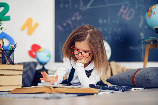 Smart little schoolgirl with digital tablet in a classroom. - Valokuva, kuva