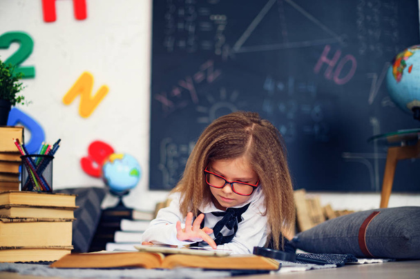 Smart little schoolgirl with digital tablet in a classroom. - Foto, afbeelding