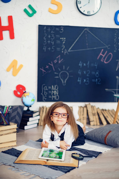 Smart little schoolgirl with digital tablet in a classroom. - Fotografie, Obrázek