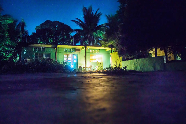 Задний двор ночью с теплицей и освещенными комнатами и террасой, Бакалар, Мексика
 - Фото, изображение