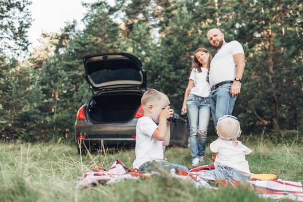 夏を楽しむ 4 人家族週末概念のフォレストにピクニックを持つ小さな子供たちと若いカップル - 写真・画像