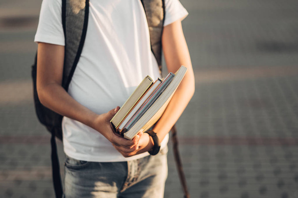 Portrait of a Little Boy in White T-Shirt and Jeans Holding Books in Hands - Foto, Imagen