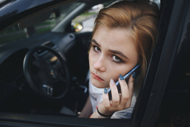 Девушка-подросток, сидящая в машине и разговаривающая по мобильному телефону
 - Фото, изображение