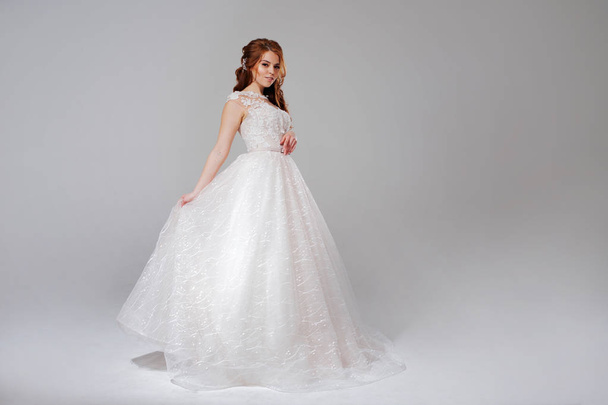 Lovely young woman bride in lavish wedding dress. Light background. - Фото, изображение