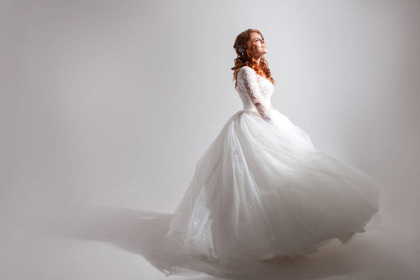 Lovely young woman bride in a lavish wedding dress. Light background. - Fotó, kép