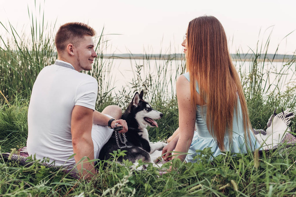 Giovane coppia divertirsi con il loro cane Haski al tramonto al di fuori della città sulla natura
 - Foto, immagini
