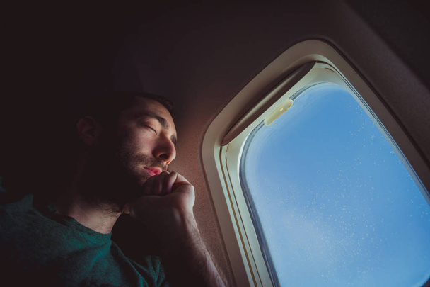 Молодой человек отдыхает и спит в самолете
. - Фото, изображение
