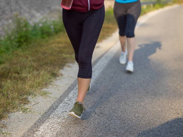 two young women jogging along country road - Photo, image