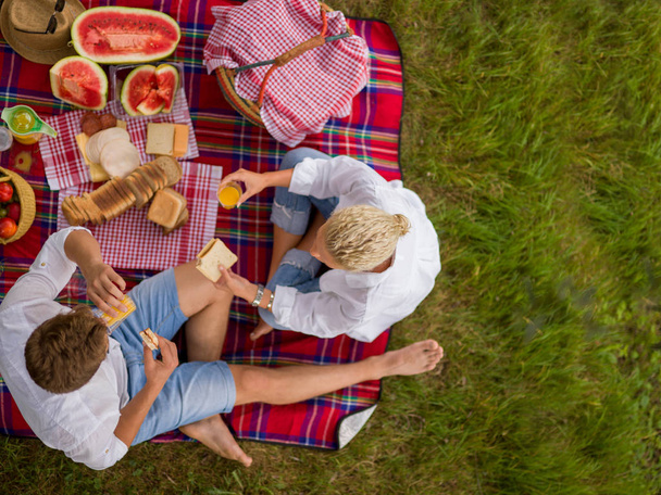 Couple in love enjoying picnic time while sitting on plaid - Valokuva, kuva