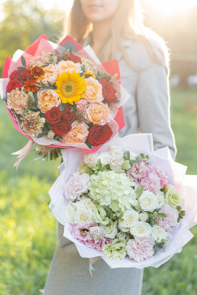 bright and delicate, pink and red, two beautiful bouquet. Young girl holding a flowers arrangements with variety of colors. Bright dawn or sunset sun - Foto, Imagem