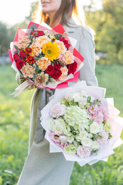 bright and delicate, pink and red, two beautiful bouquet. Young girl holding a flowers arrangements with variety of colors. Bright dawn or sunset sun - Photo, Image