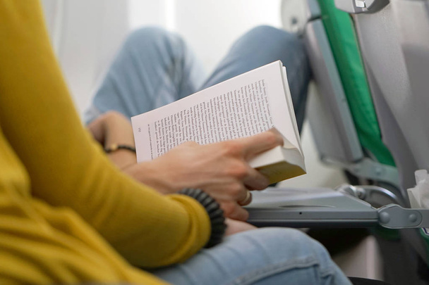 Genç bir adam karısıyla uçak ile ilgili bir kitap okur. Uçakla seyahat bir adam. Uçan bir kitabı okuma bir adam. Taşıma kavramı - Fotoğraf, Görsel