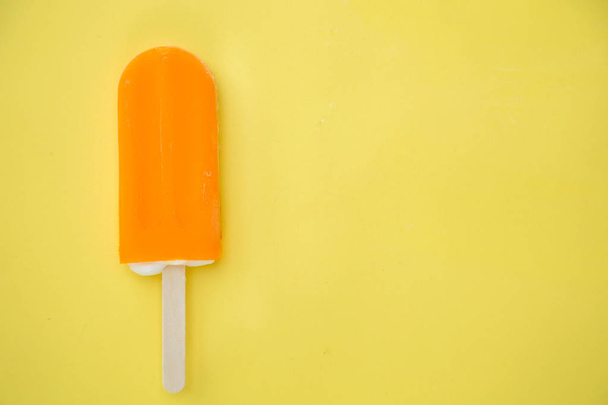 orange popsicle on a yellow background - Foto, Imagen