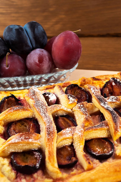 Tarte à la pâte aux prunes, cuite au four, plaque de verre aux prunes, fond bois, cadre vertical
. - Photo, image