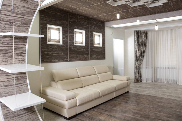Modernes Design des Ruheraums mit kombinierten Holzparkettleuchten mit weißem Sofa und großem Plasma-TV an einer dunklen Holzwand - Foto, Bild