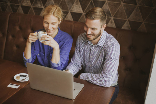 Jeune couple travaillant sur ordinateur portable dans un café
 - Photo, image