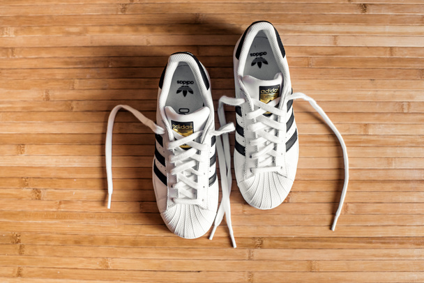 Buty sportowe Adidas Superstar z kultowego trzy niebieskie pasy na drewnianą podłogę, obejrzeli z obciążenie związane z koronki, cofnąć - Zdjęcie, obraz